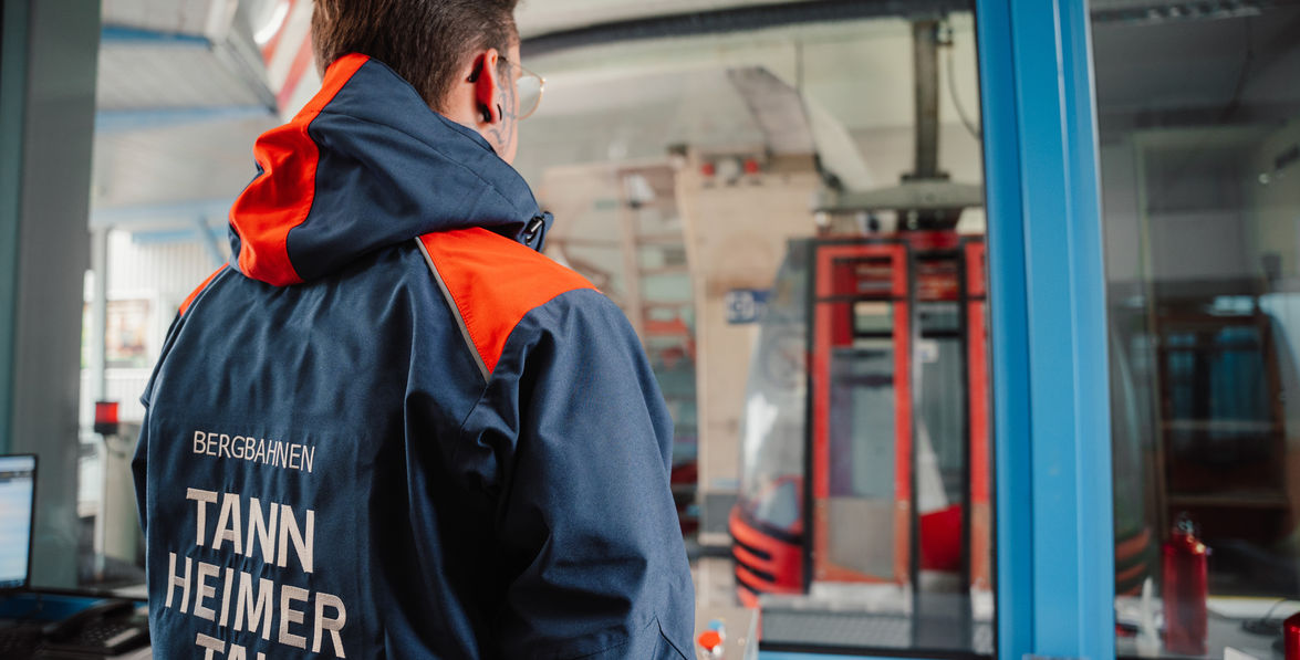 Mann in Arbeitskleidung beobachtet Gondel an Bergstation