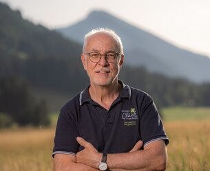 Manfred Hörbst mit verschränkten Armen vor Bergkulisse