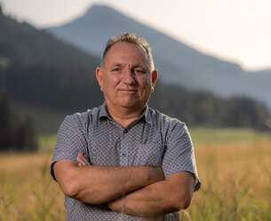 Michael Schretter mit verschränkten Armen vor Bergkulisse